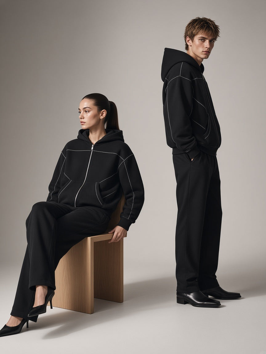 Two people in the Marcel Afters Contrast-Stitched Boxy Fleece Zip Hoodie in Black on a warm grey paper studio set