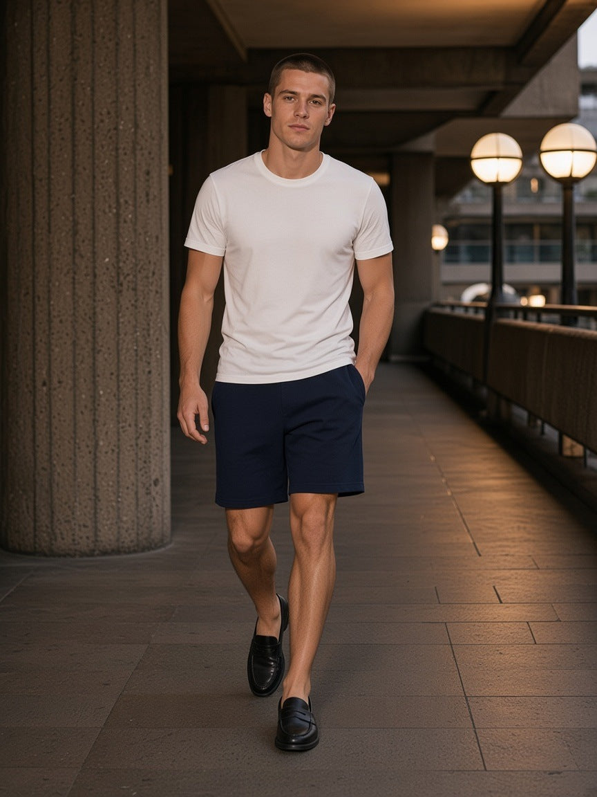 Man in Cotton Shorts in Navy Blue at the Barbican in London at night