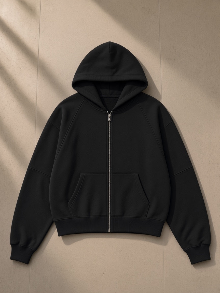 Cropped zip-through hoodie in Black, laid flat on pale limestone, front view