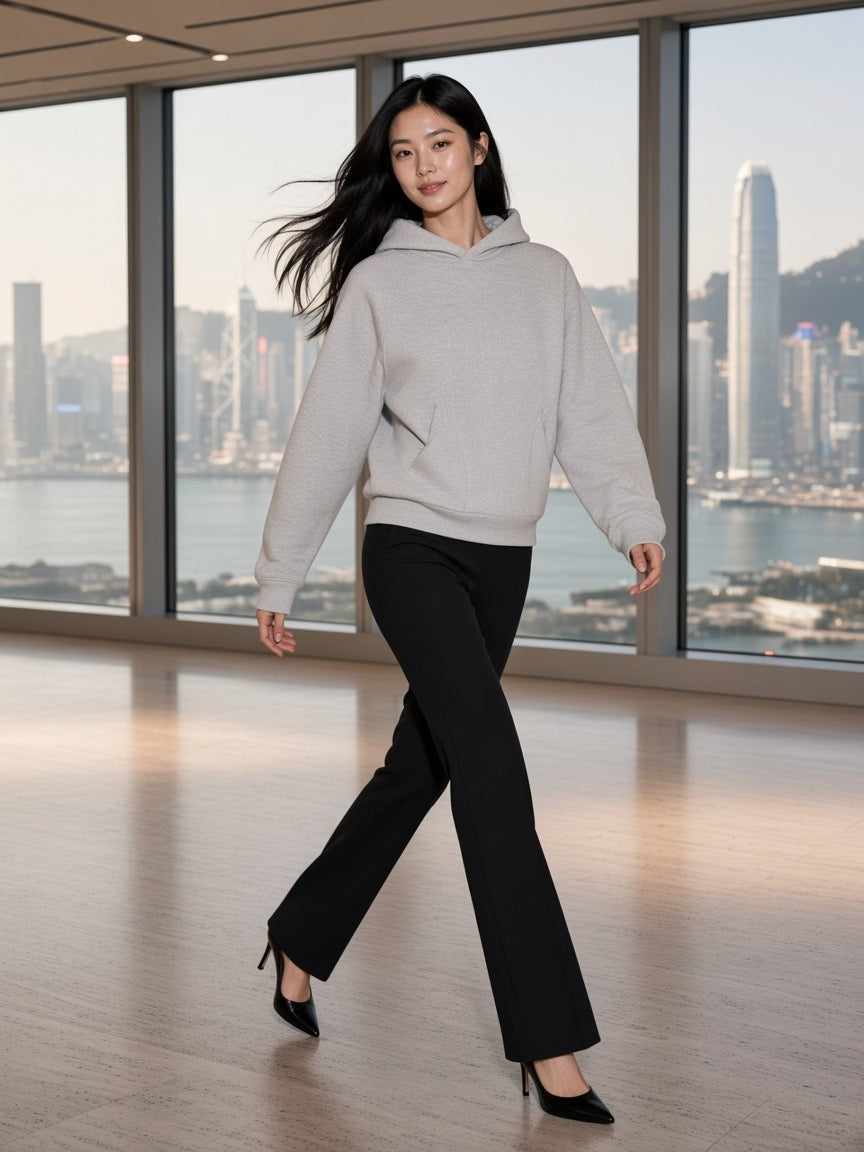 Woman in the Curved Panel Raglan Hoodie in Flower Gray standing in a Hong Kong harbour penthouse by day