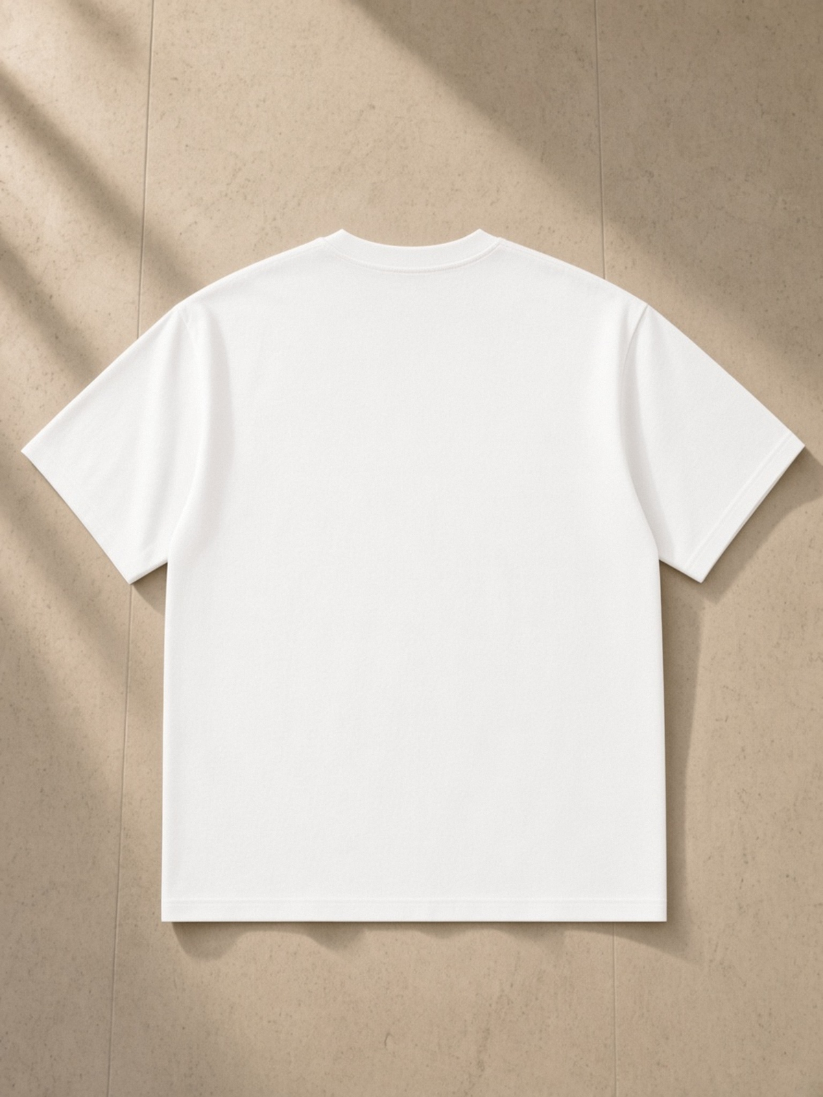 Pure Cotton T-Shirt in White, laid flat on pale limestone, back.