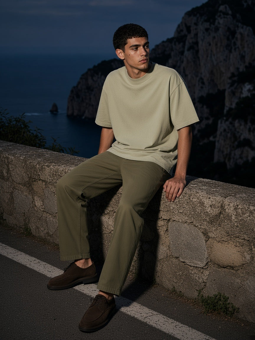 Man in the Mineral Wash Oversized T-Shirt in Apricot seated on a stone wall on the Via Krupp in Capri at night