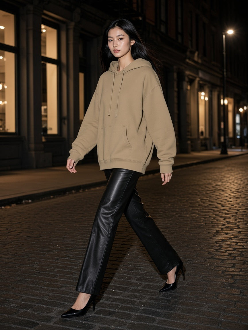 Woman in the Marcel Afters Oversized Drop Shoulder Hoodie in Khaki walking a SoHo street in New York at night