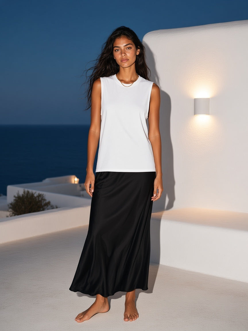 Woman in the Marcel Afters Raw Edge Cotton Tank Top in White on a whitewashed hotel terrace on Mykonos at dusk