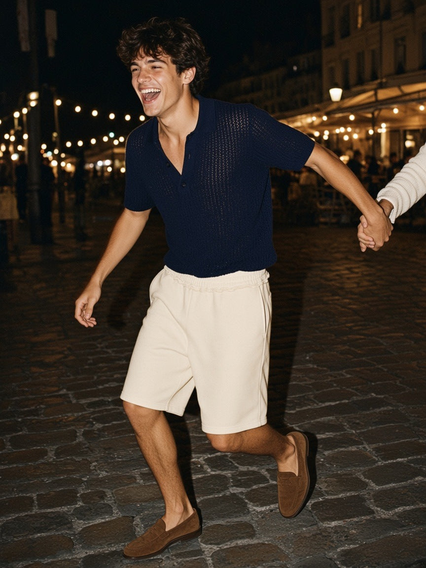 Man in the Marcel Afters Raw Edge Fleece Shorts in Flower Gray at a cliffside hotel pool on the Cote d'Azur at night