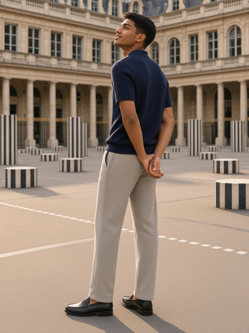 Man in Stone Gray snow washed straight leg pants and a navy knit polo in the Palais-Royal courtyard