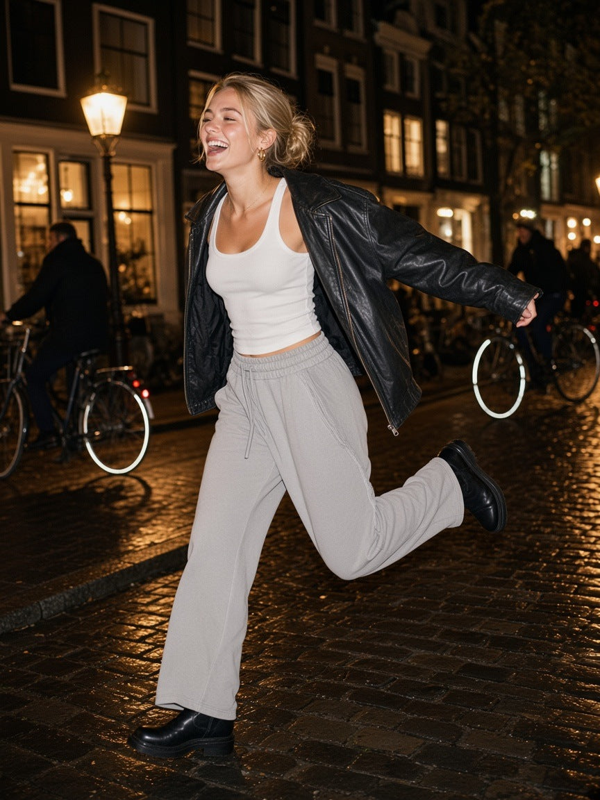 Woman in the Snow Washed Tape Raw Edge Sweatpants in Light Gray, skipping along an Amsterdam canal at 1am