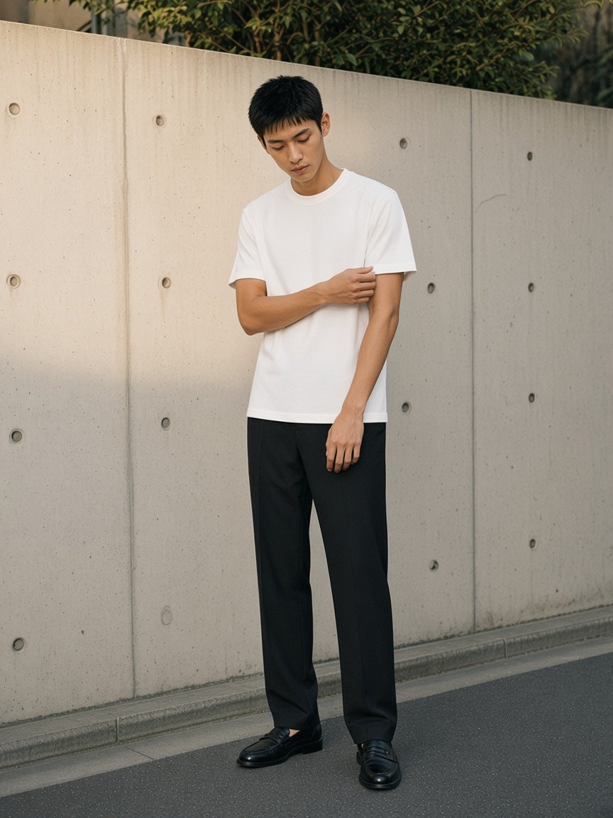 Man in the Solid Color Regular Fit T-Shirt in White against a concrete wall in Aoyama, Tokyo in the morning