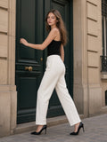Woman in the Tapered Straight Hem Sweatpants in White with a black cami and heels, pushing open a green street door in Paris in the morning