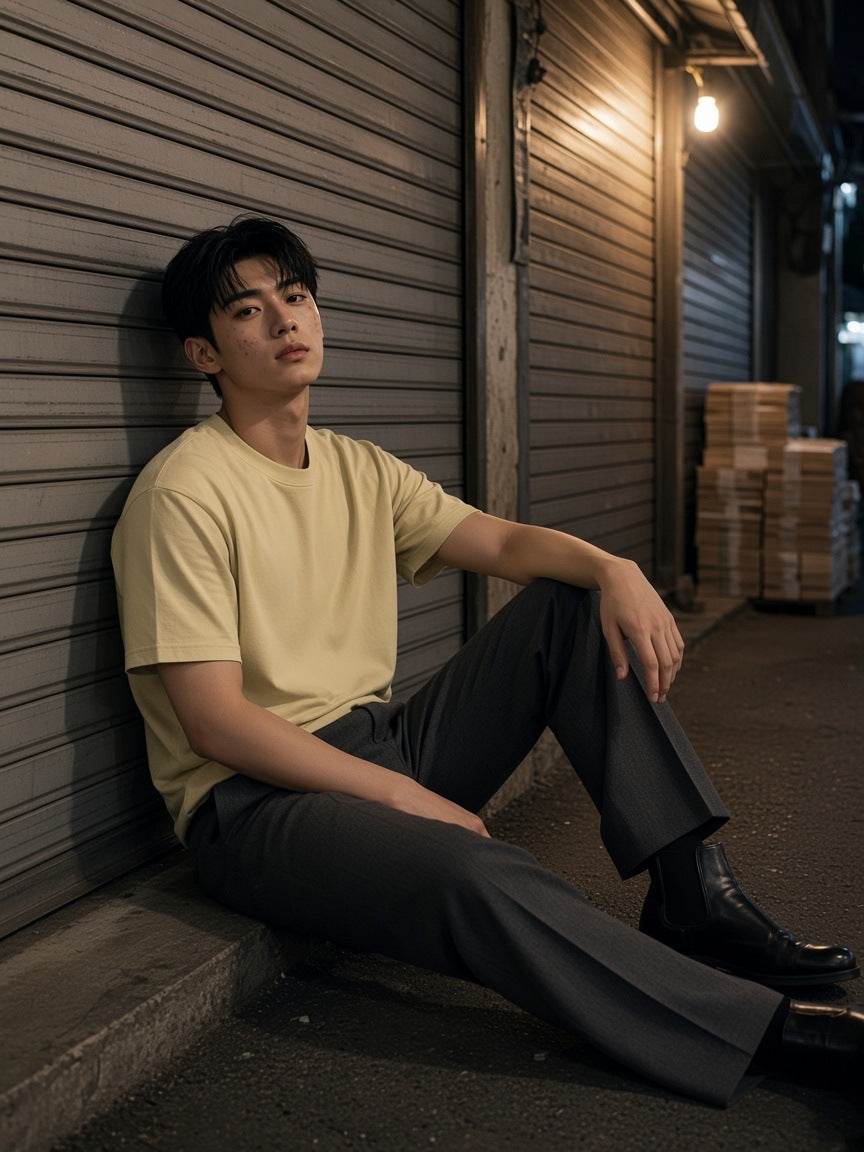 Man in the Vintage Wash Distressed T-Shirt in Khaki seated against a shutter in a Euljiro lane in Seoul at night