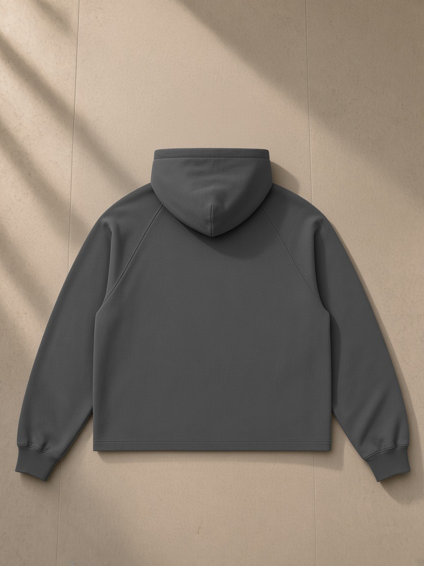 Vintage wash raw edge boxy hoodie in Dark Gray, laid flat on pale limestone, back view