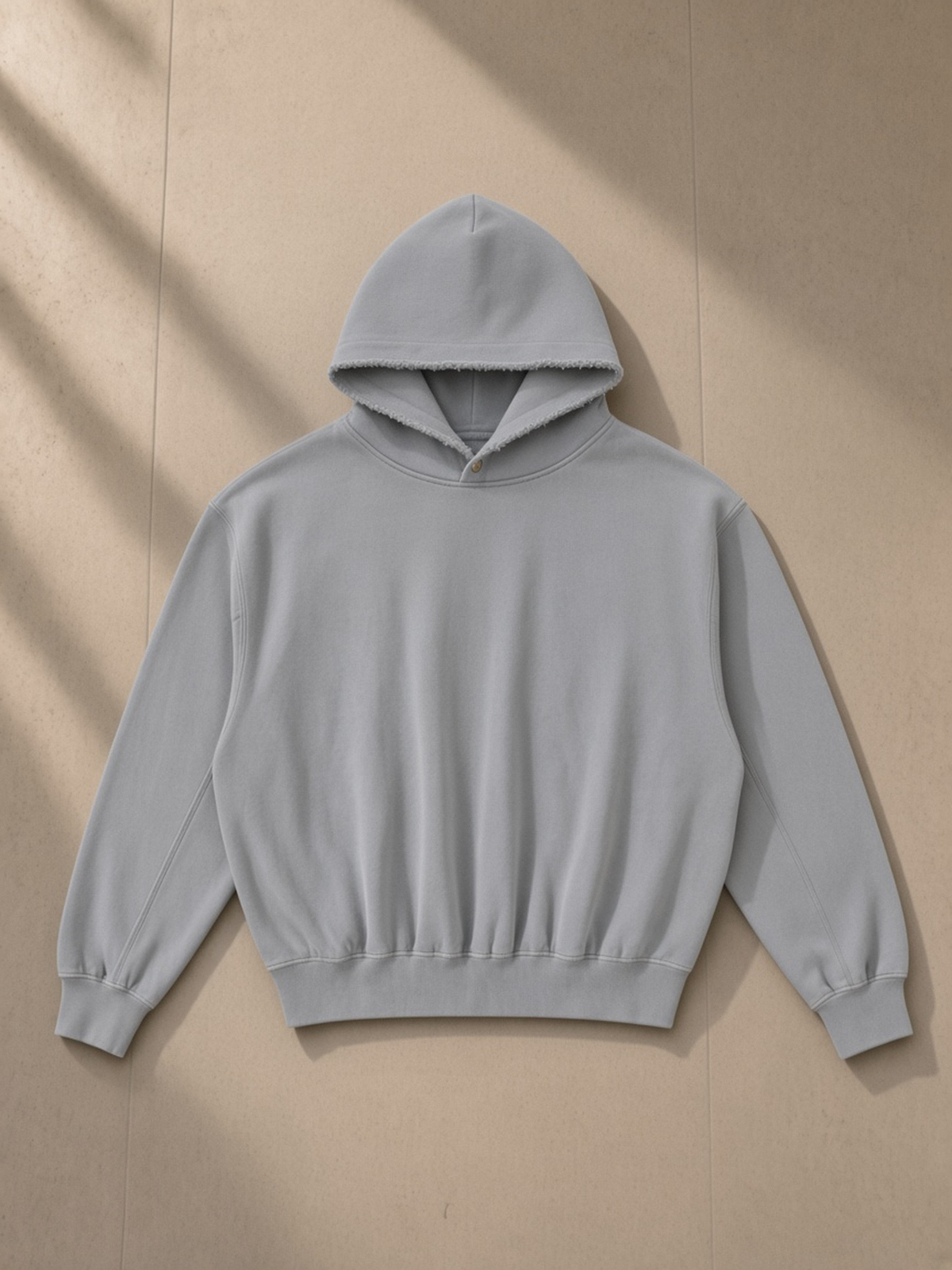 Frayed Enzyme Washed Fleece Hoodie in Light Gray, laid flat on pale limestone