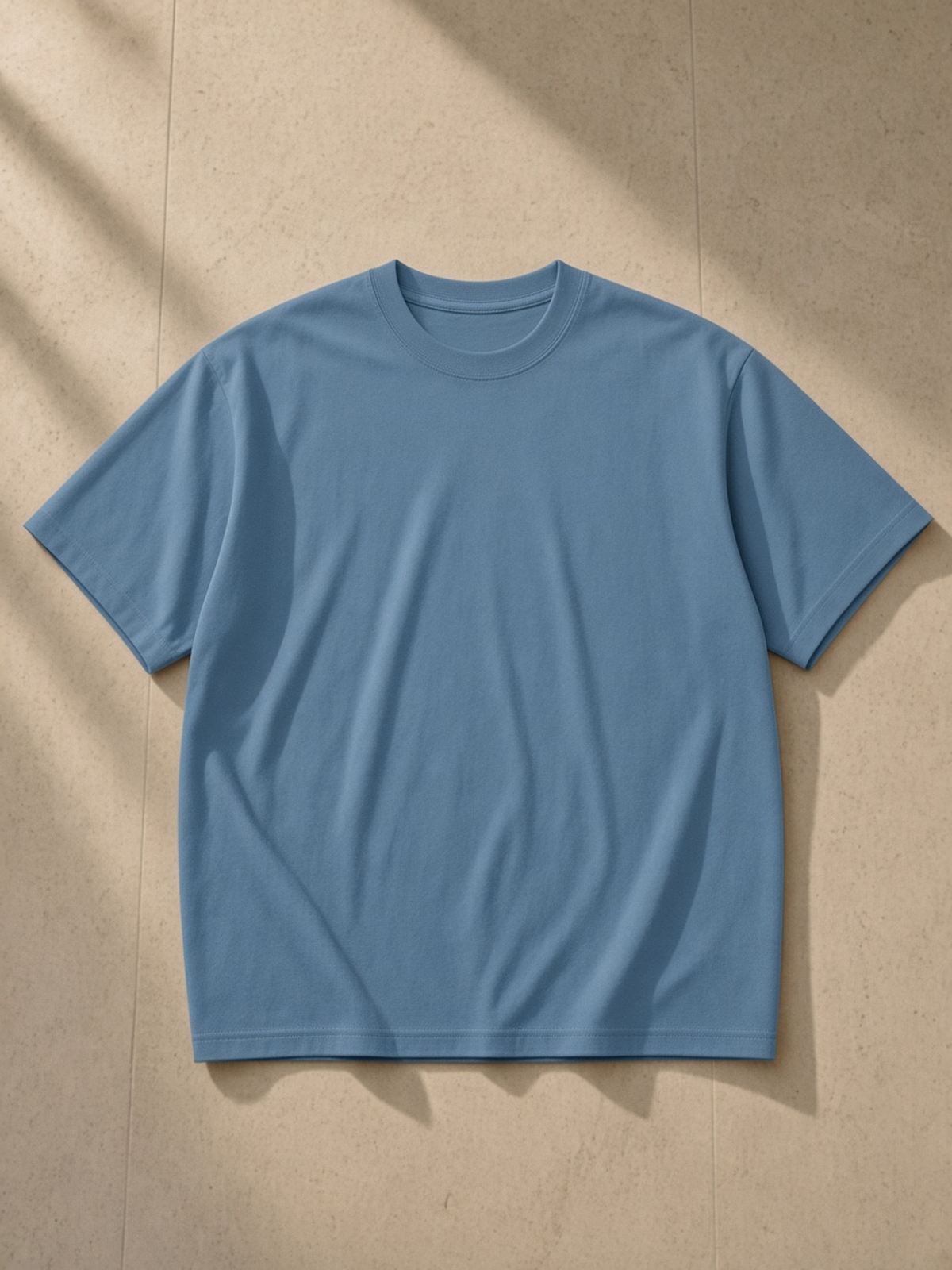 Oversized Drop Shoulder T-Shirt, 200 gsm in Haze Blue, laid flat on pale limestone, front.