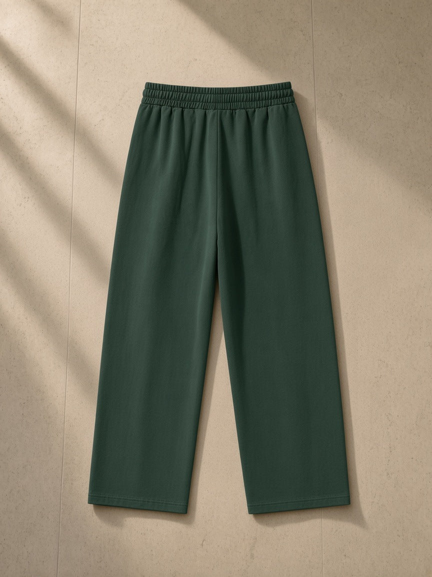 Heavyweight vintage wash sweatpants in Blackish Green, laid flat on pale limestone, back view