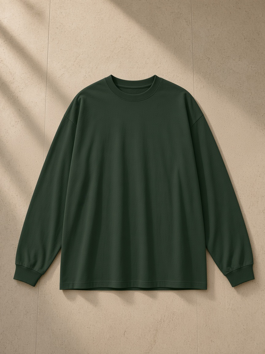 Oversized Long Sleeve T-Shirt in Blackish Green, laid flat on pale limestone