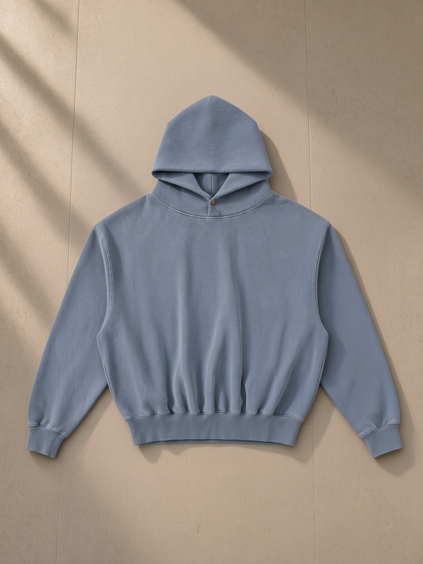 Frayed Enzyme Washed Fleece Hoodie in Blue, laid flat on pale limestone