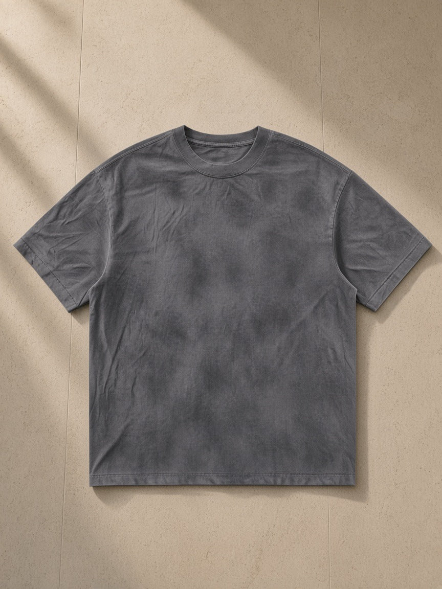 Dirty Washed Loose T-Shirt in Washed Charcoal, laid flat on pale limestone