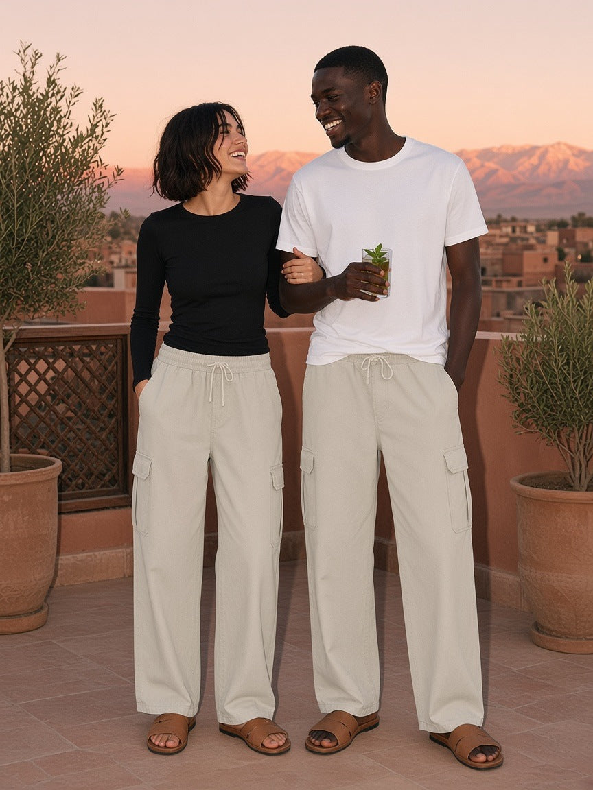 Marcel Afters Drawstring Waist Straight-Leg Cargo Pants in Light Gray, worn by a man and a woman, arm in arm on a terracotta rooftop at sunset in matching stone cargo pants