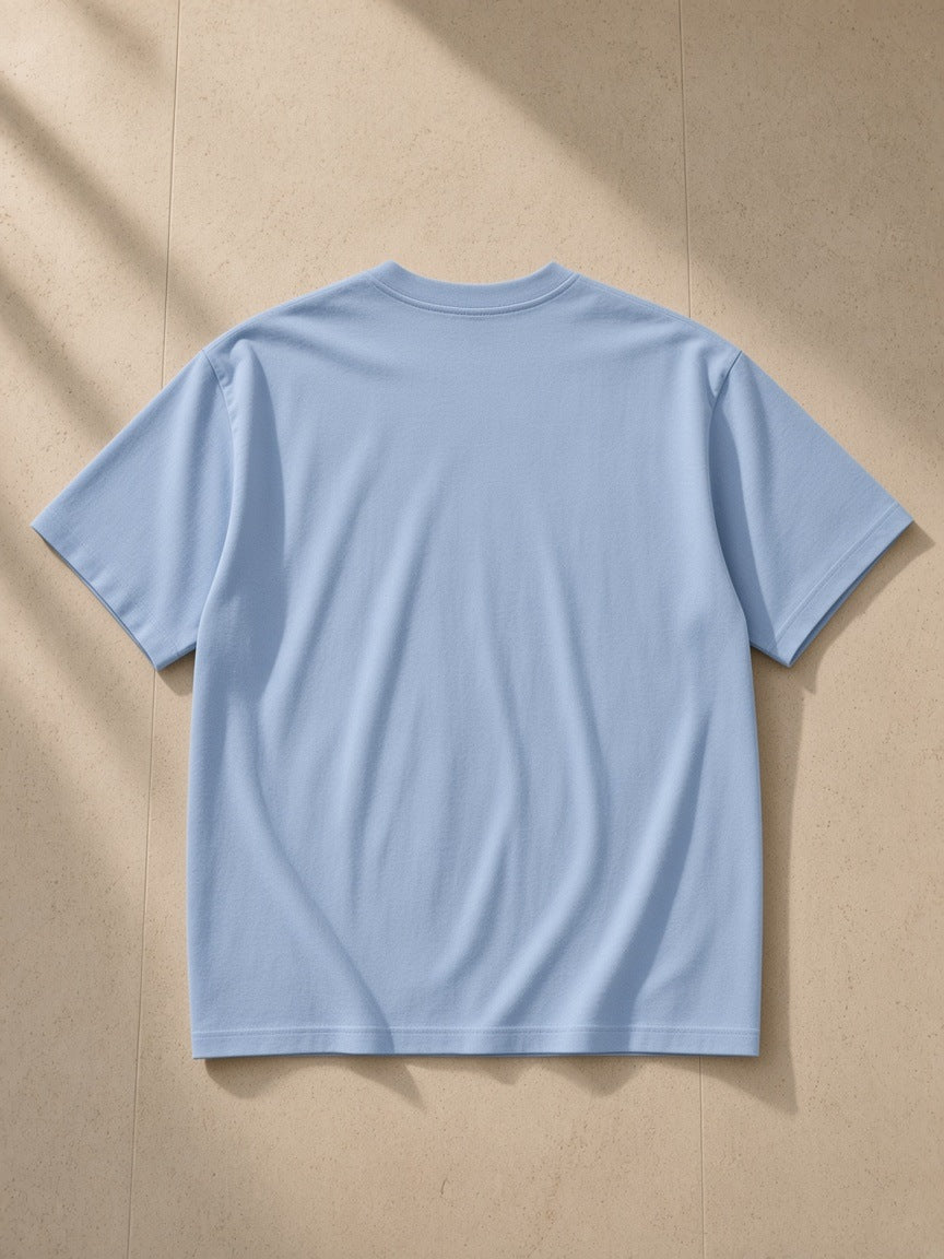 Drop Shoulder Cotton T-Shirt in Blue, laid flat on pale limestone, back view
