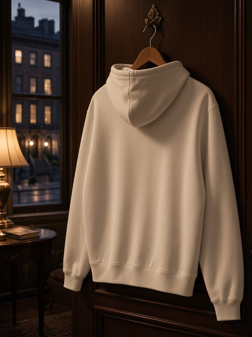Women's Drop Shoulder Full Zip Hoodie in White on a wooden hanger hooked on a lacquered suite door in a Carlyle-style hotel suite at night