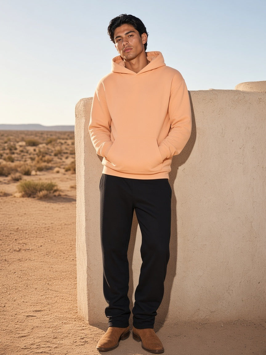 Man in the Drop Shoulder Hoodie in Apricot leaning on an adobe wall in Marfa, Texas in the morning