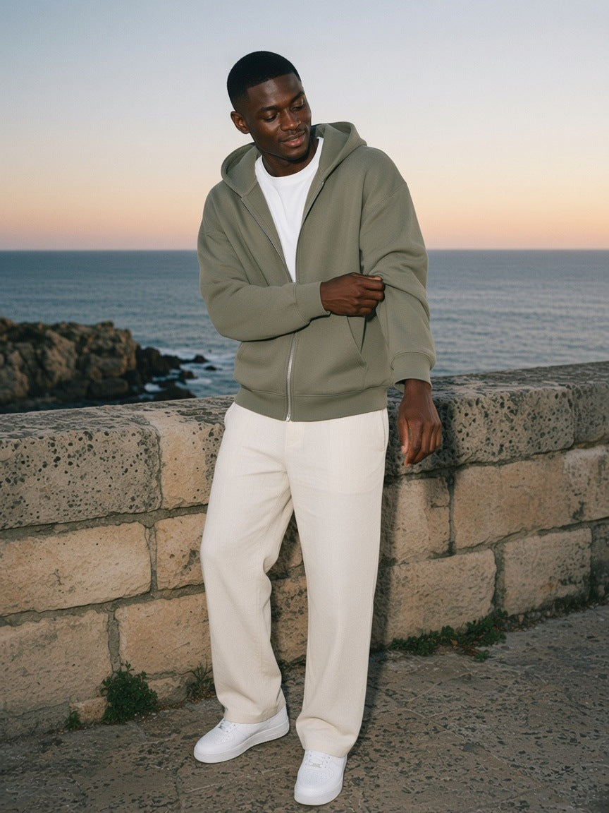 Man in the Marcel Afters Drop-Shoulder Zip Up Hoodie in Gray Green on a limestone sea terrace at dusk in Cape Town