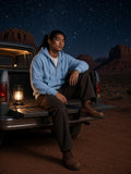 Man in the Drop-Shoulder Zip Up Hoodie in Sky Blue seated on a pickup tailgate under desert stars at night