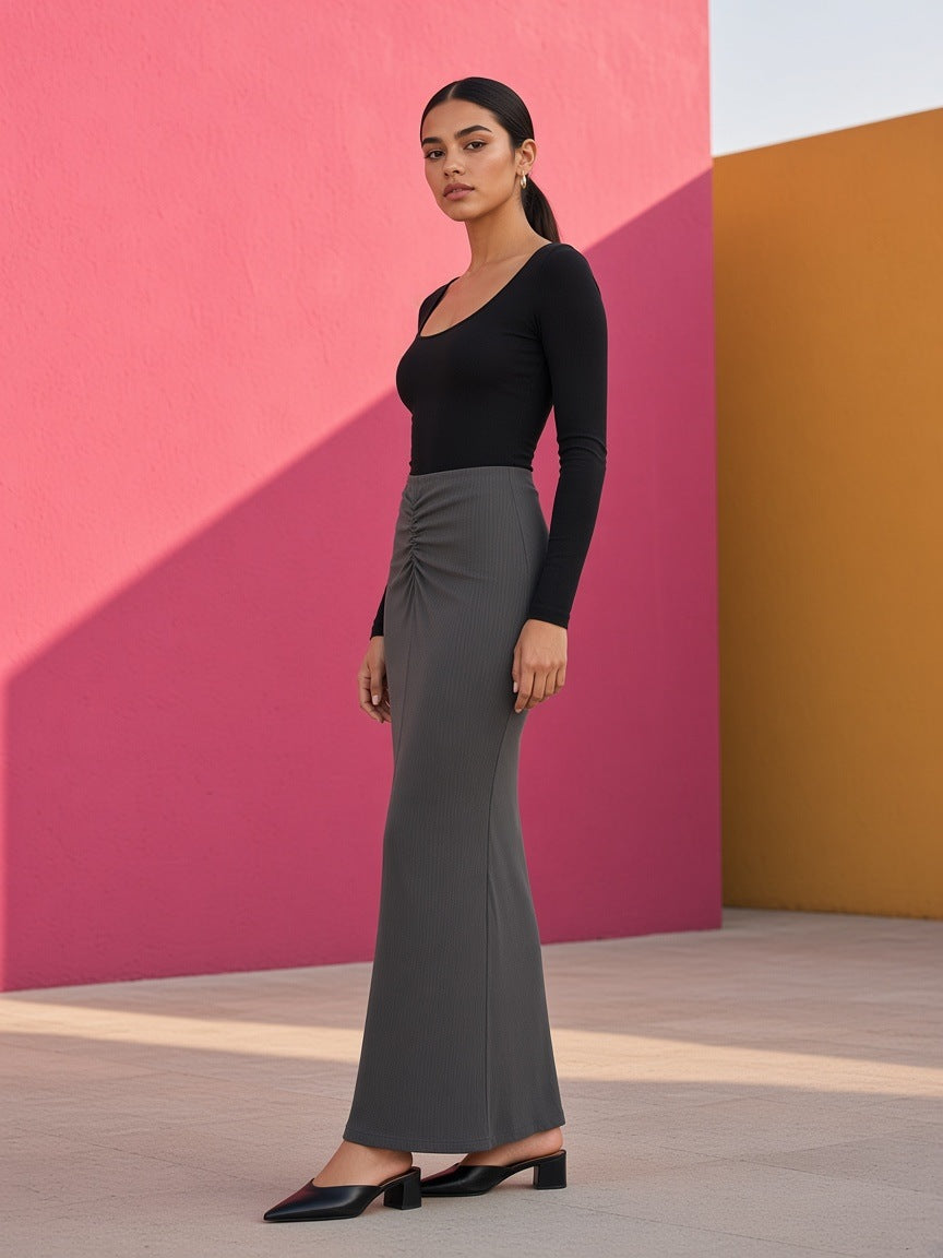 Woman in the Marcel Afters Dyed Washed Drawstring Maxi Skirt in Dark Gray against a pink Barragan wall in Mexico City at dusk