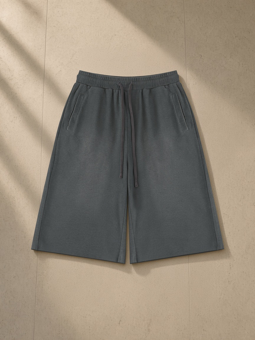 Unisex sunfade raw edge shorts in Gray, laid flat on pale limestone