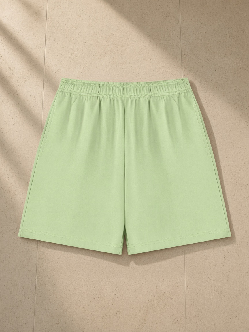 Cotton Shorts in Light Green, laid flat on pale limestone