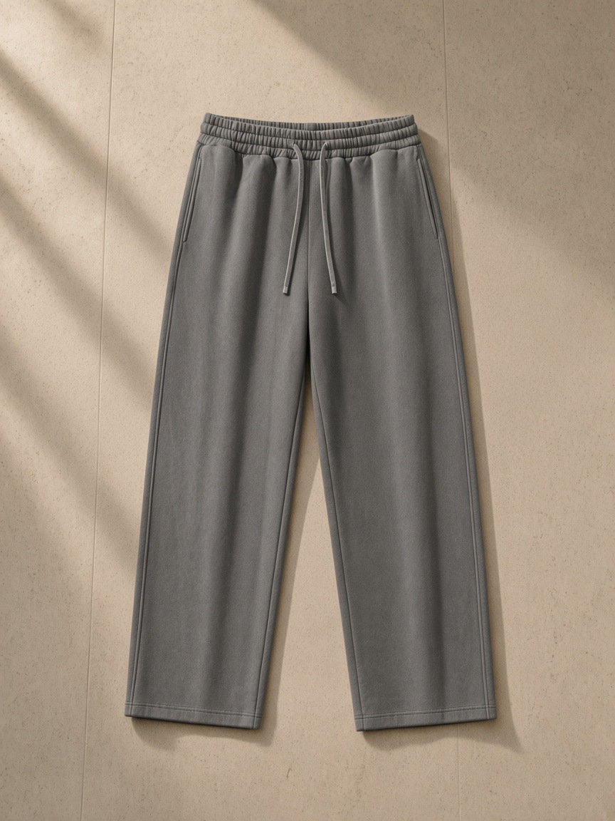 Unisex straight-leg sweatpants in Dark Gray, laid flat on pale limestone