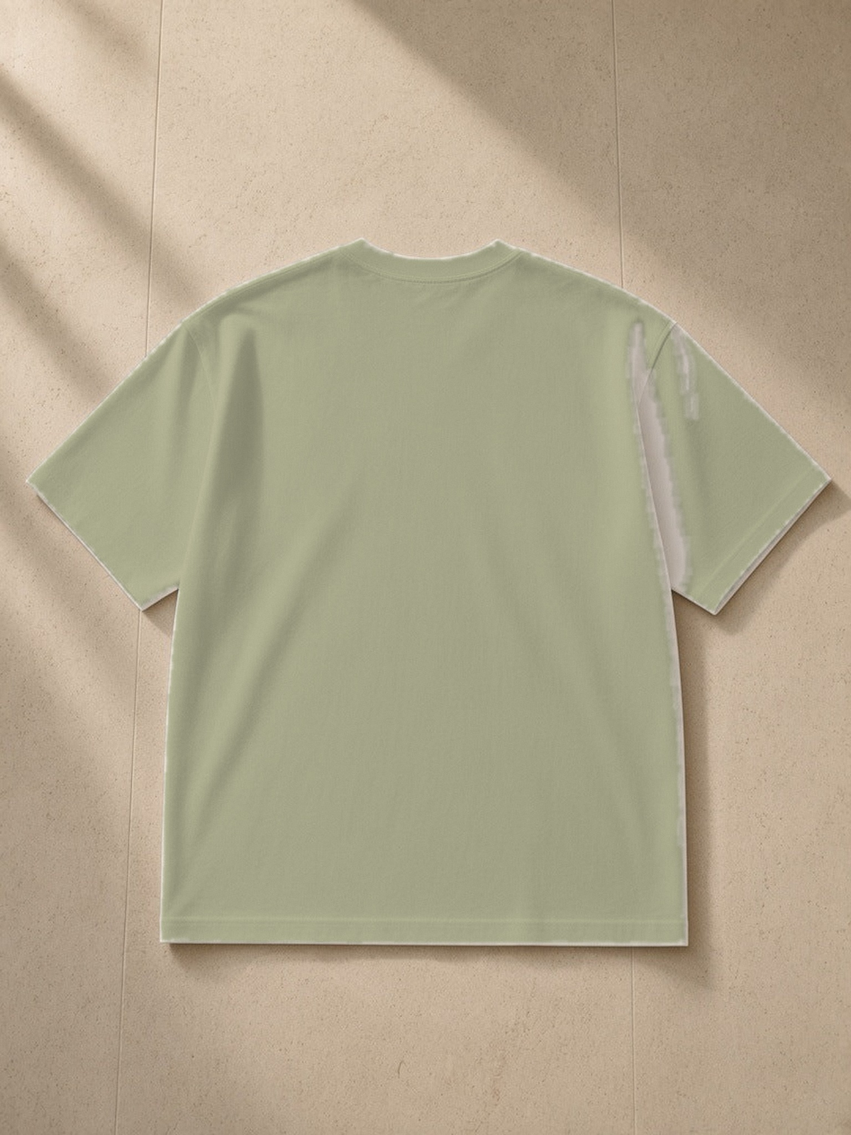 Women's Heavyweight Drop Shoulder T-Shirt in Grey Green, laid flat on pale limestone, back.