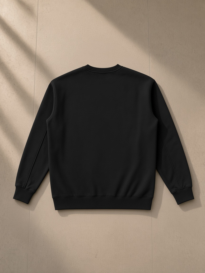 Essential heavyweight crewneck sweatshirt in Black, laid flat on pale limestone, back view