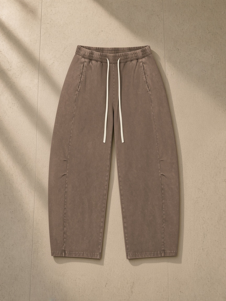 Unisex mineral wash barrel leg pants in Coffee, laid flat on pale limestone