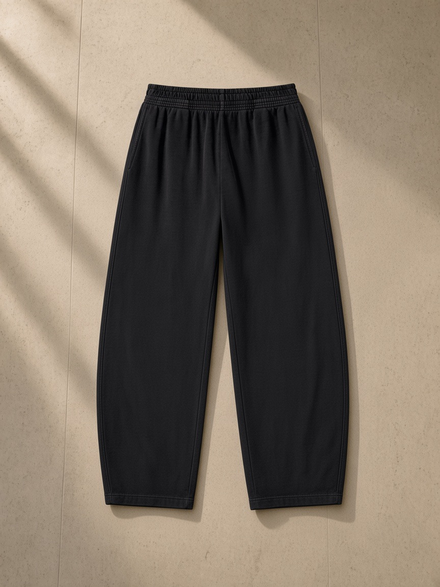 Vintage washed barrel leg sweatpants in Black, laid flat on pale limestone