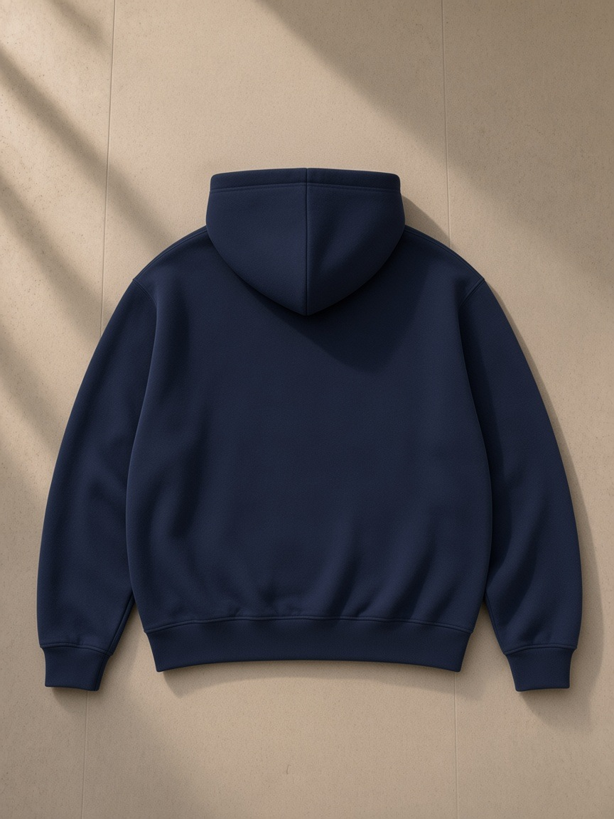 Unisex heavyweight fleece boxy hoodie in Navy Blue, laid flat on pale limestone, back view