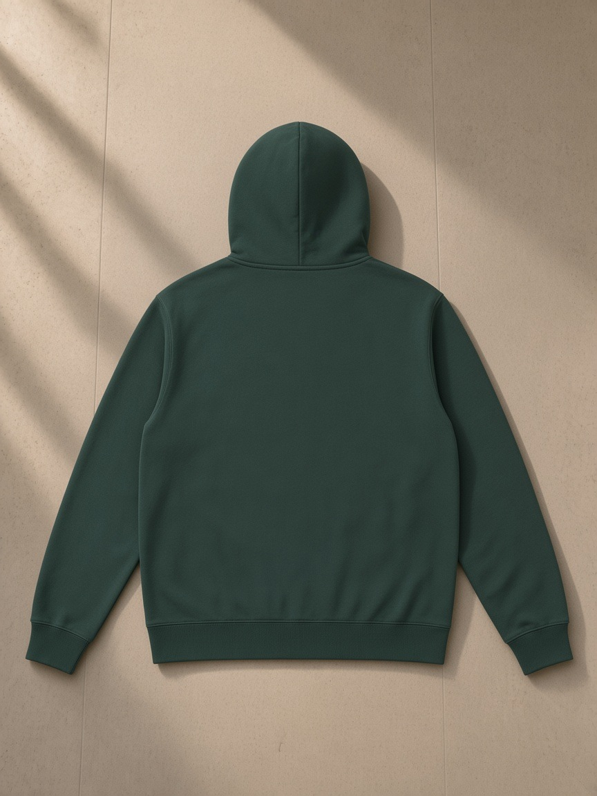 Essential oversized hoodie in Retro Green, laid flat on pale limestone, back view