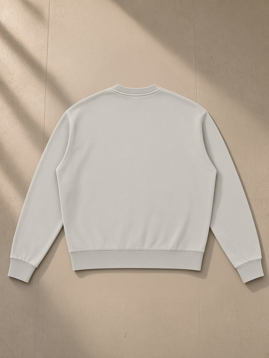 Unisex vintage wash crewneck sweatshirt in Light Gray, laid flat on pale limestone, back view