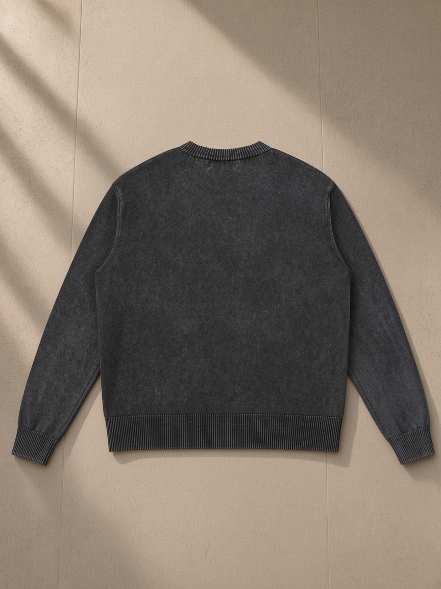 Mineral Wash Crewneck Sweater in Black, laid flat on pale limestone, back view