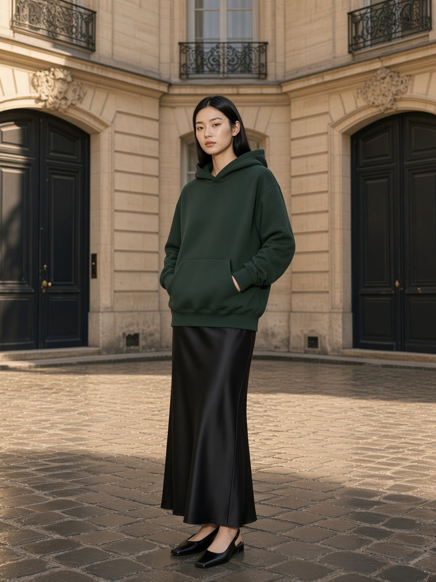 Woman in the Essential Boxy Heavyweight Drop-Shoulder Hoodie in Blackish Green in a limestone courtyard in the morning in Paris