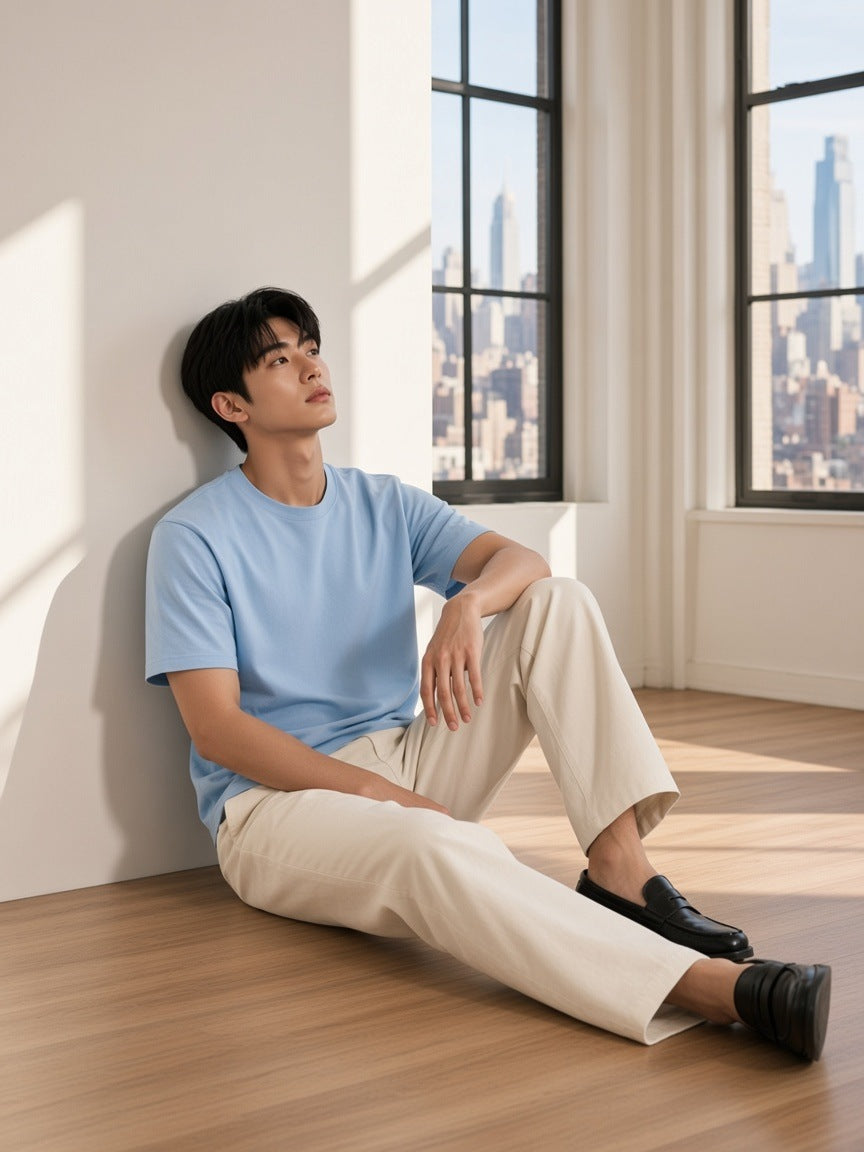 Man in the Essential Cotton Boxy T-Shirt in Sky Blue standing in a Tribeca loft in New York in the morning