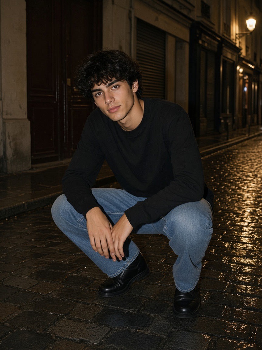 Man in the Essential Cotton Long Sleeve T-Shirt in Black squatting on wet Paris cobbles at night