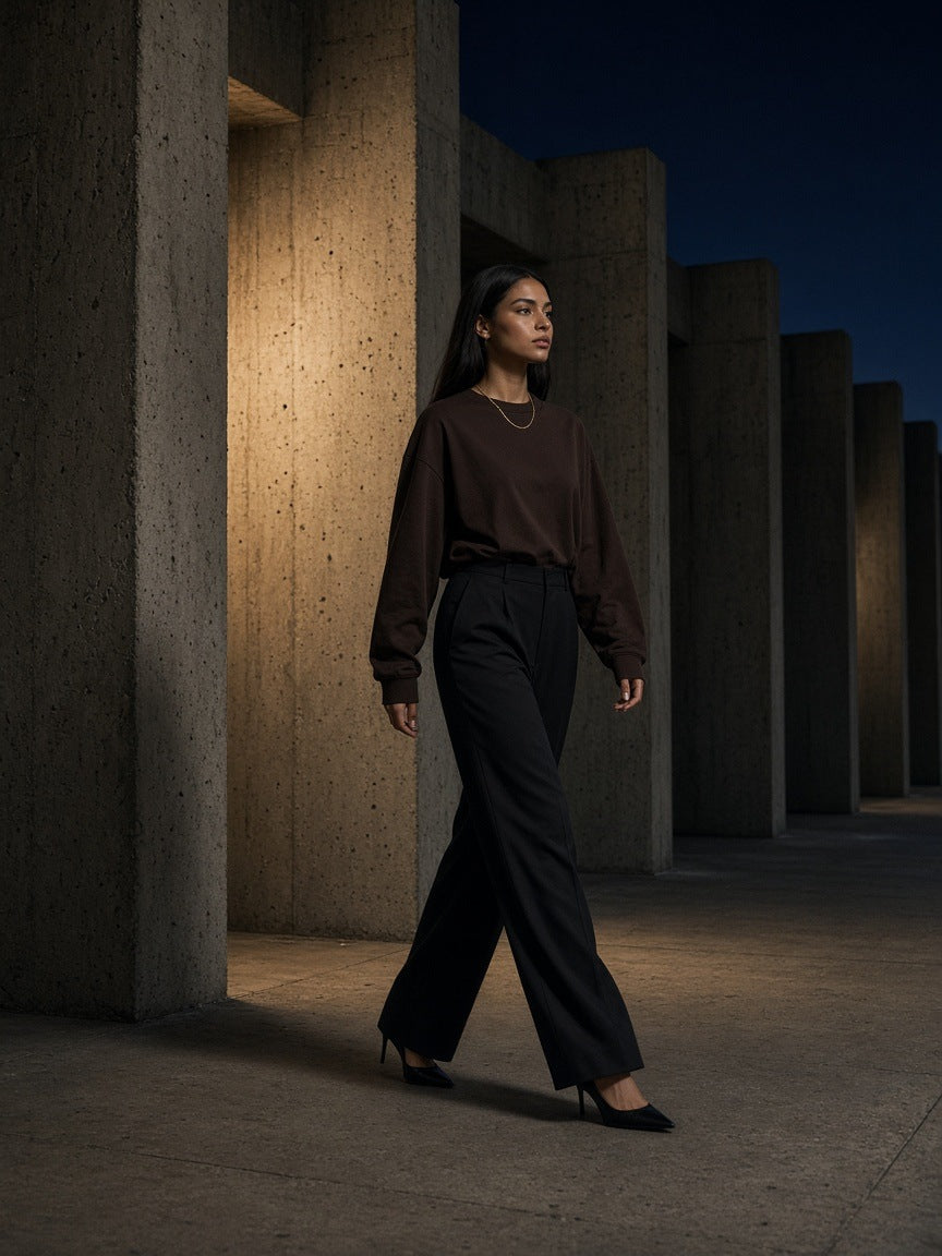 Woman in the Essential Cotton Long Sleeve T-Shirt in Coffee on a Brutalist walkway in London at night