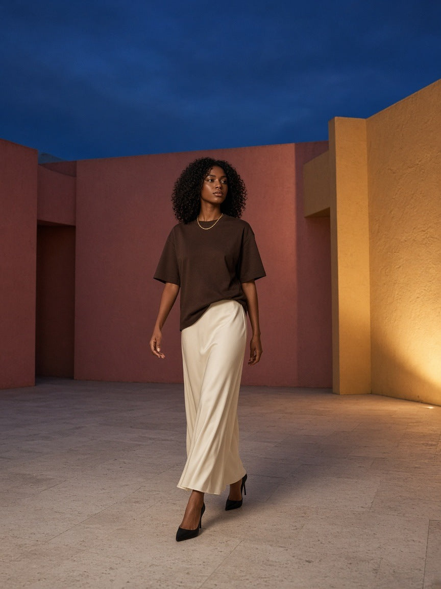 Woman in the Marcel Afters Essential Cotton T-Shirt in Coffee in a rose-pink courtyard in Mexico City at dusk