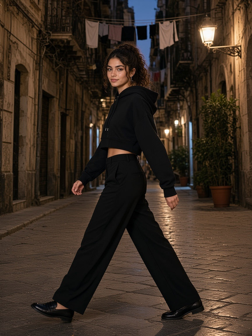 Woman in the Essential Cropped Hoodie in Black walking a street in Palermo at night