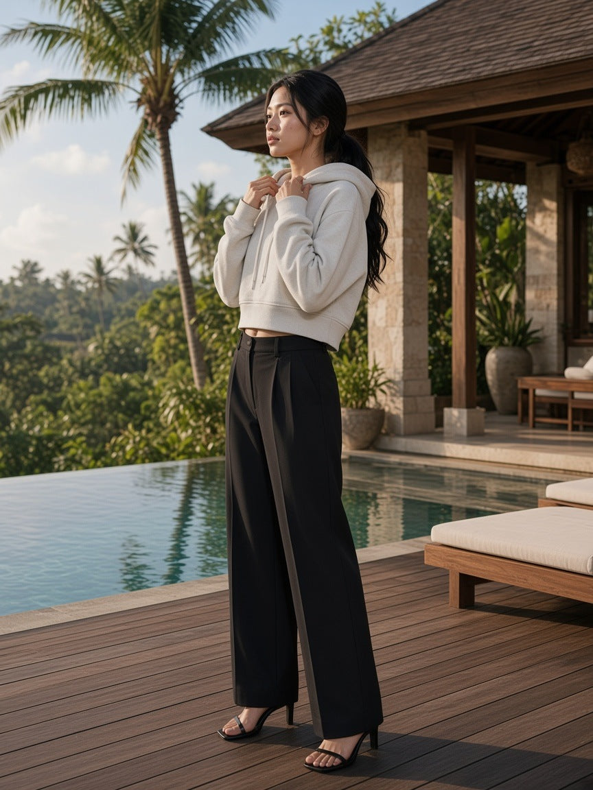 Woman in the Essential Cropped Hoodie in Oat Gray standing by a villa pool in Bali in the morning