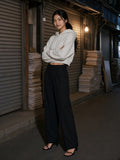 Woman in the Essential Cropped Hoodie in Oat Gray with high-rise black trousers, in a print-shop lane in Euljiro, Seoul at night