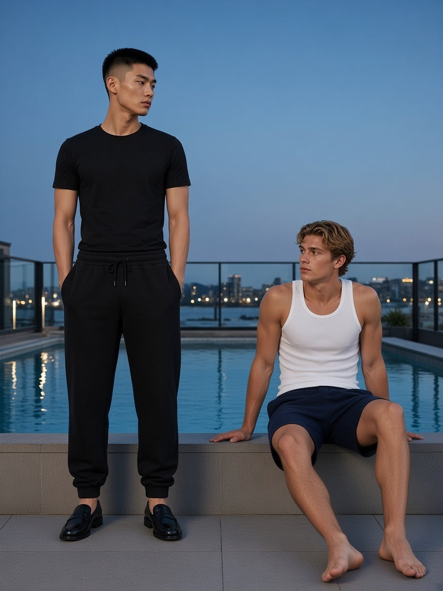Two people in Essential Drawstring Jogged Sweatpants and range shorts on a rooftop hotel pool deck in Sydney at blue hour