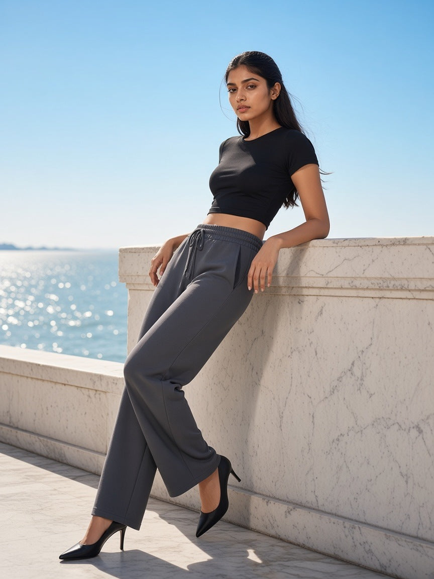 Woman in Essential Drawstring Straight-Leg Sweatpants in Charcoal Gray with heels on a marble sea terrace in Mumbai in the morning