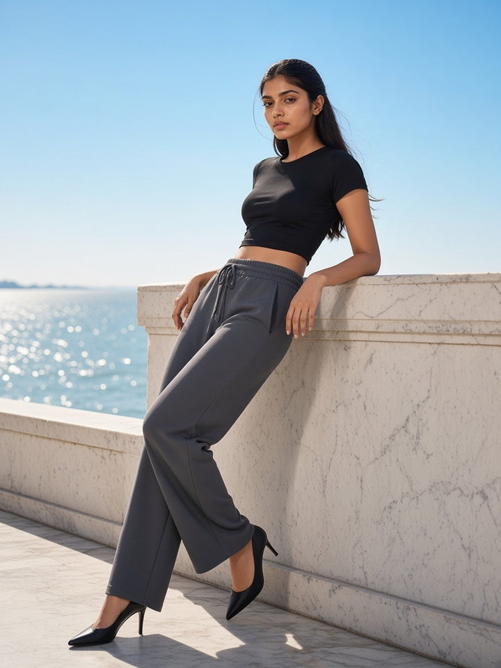 Woman in Essential Drawstring Straight-Leg Sweatpants in Charcoal Gray with heels on a marble sea terrace in Mumbai in the morning